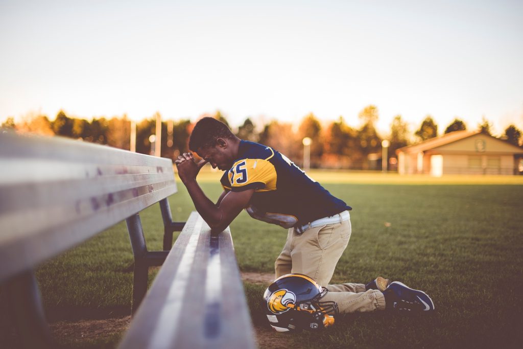 Athlete kneels on the ground praying